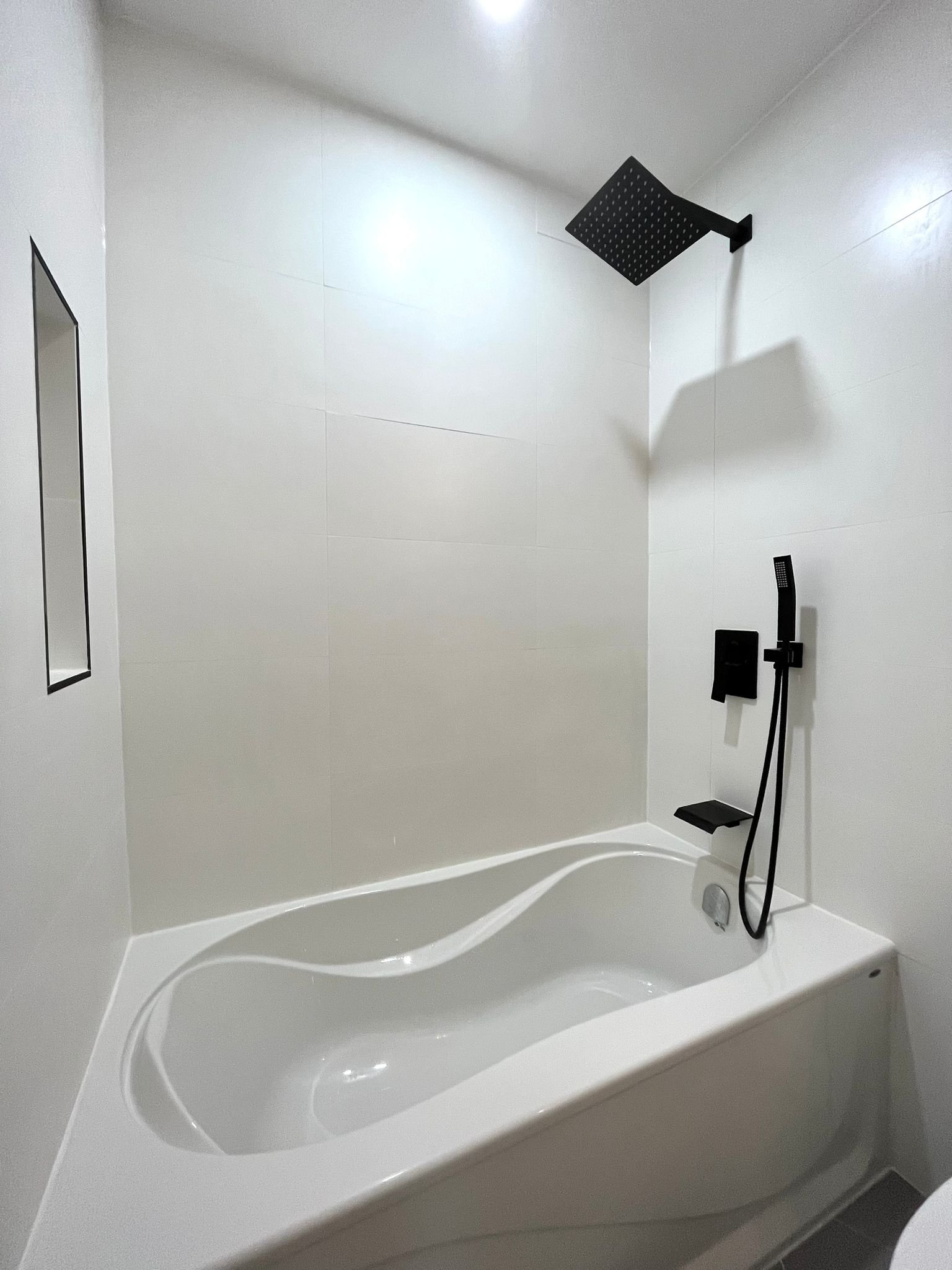 White alcove bathtub with black shower fixtures