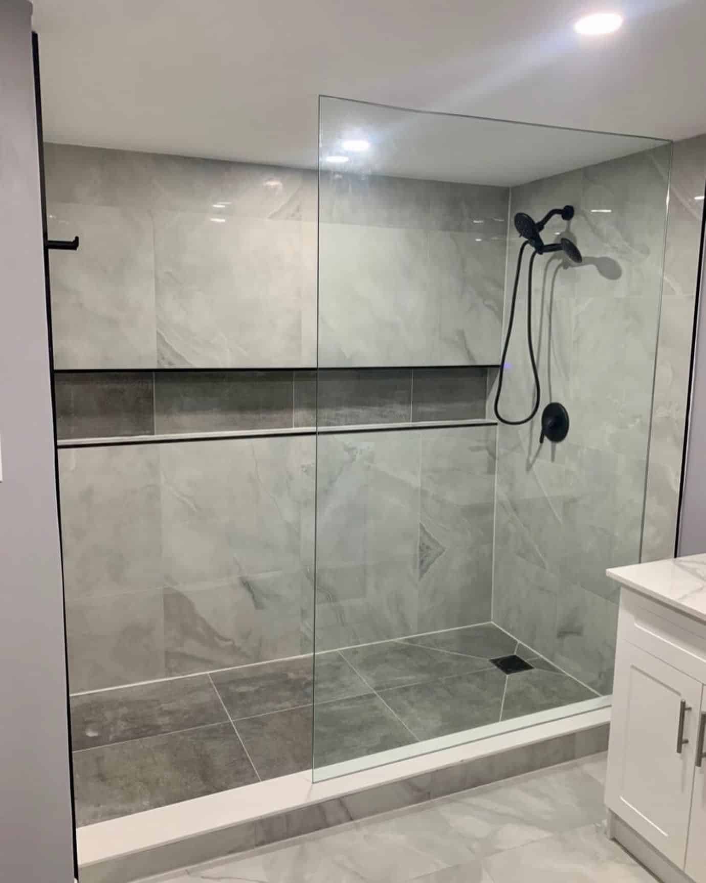 Walk-in shower with grey tile, long niche and glass panel