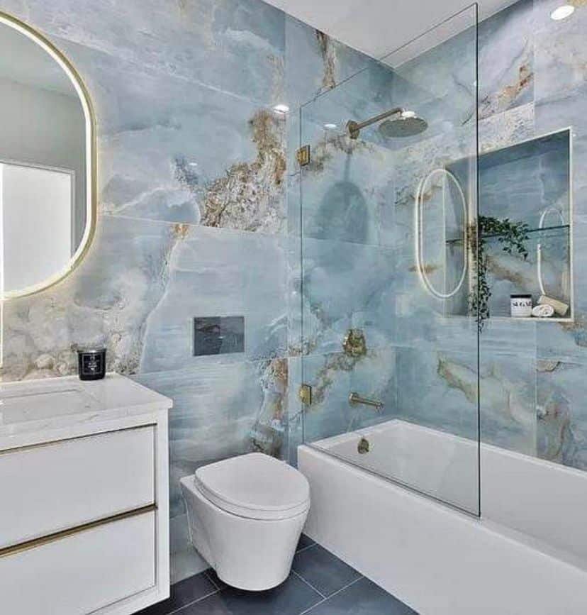 bathtub shower whit blue porcelain tiles and wall mount toilet