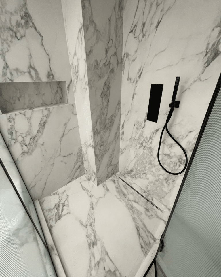 stand up shower with black shower fixtures and marble tiles