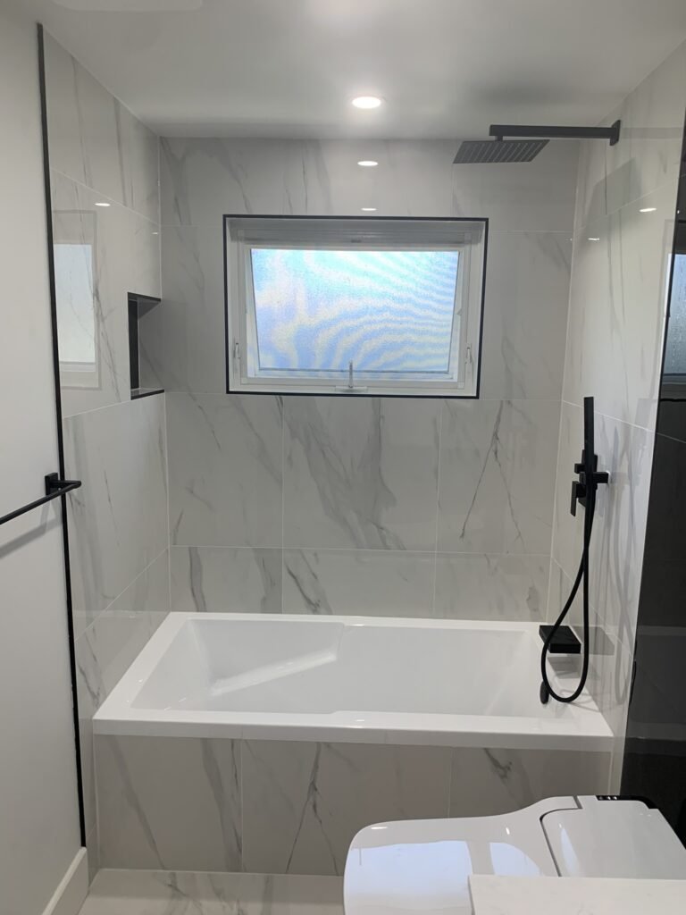 Drop in bathtub shower with black shower fixtures and shower niche