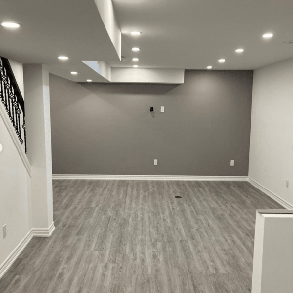 Finished basement with a cozy living area, including a sectional sofa, coffee table, and modern lighting for a stylish, inviting space.