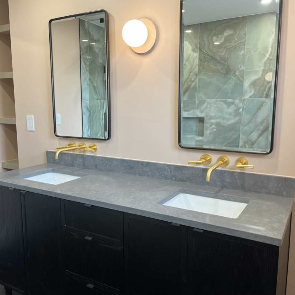 Custom double sink vanity with wall mount gold faucets and black framed mirror
