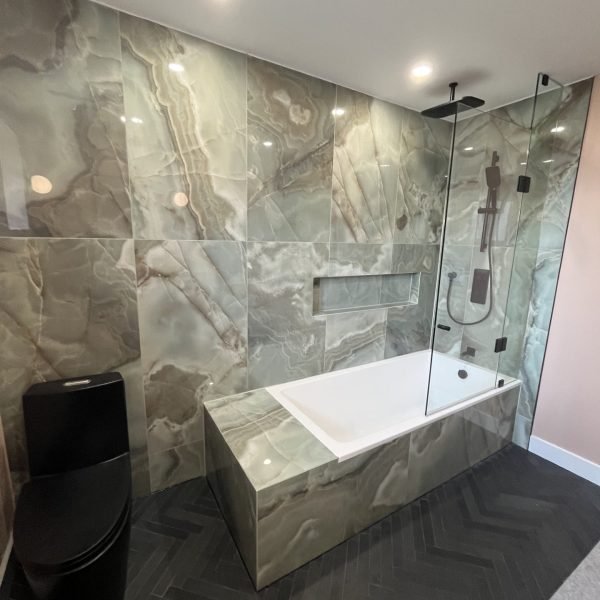 Luxury master bathroom renovation with drop in bathtub and black toilet and herringbone tiles