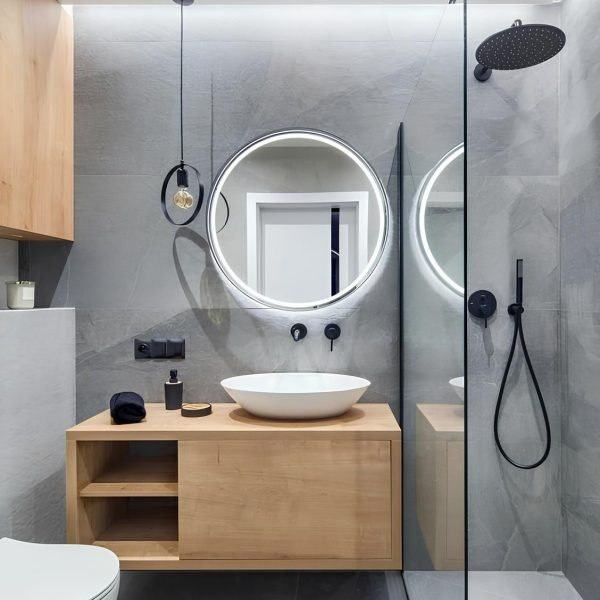 Bathroom with round LED mirror, wood vanity and glass shower