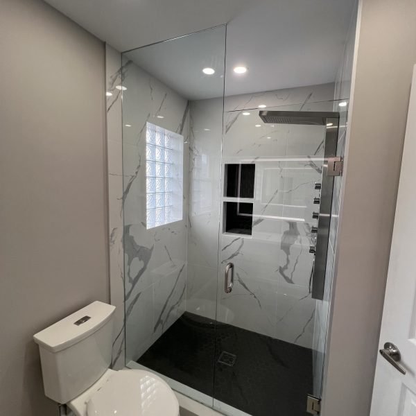 Walk-in shower with marble-look tile and black floor