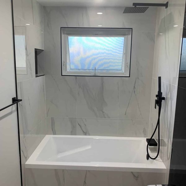 Alcove bathtub with marble-look tile and window