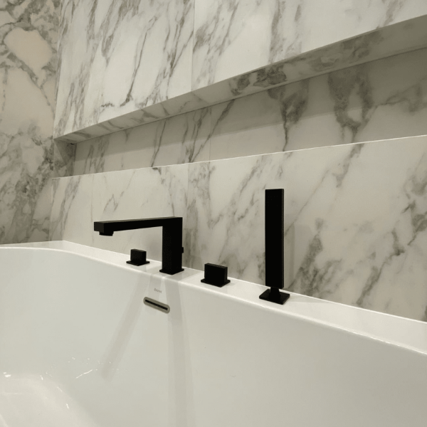 Freestanding tub with marble-look tile and black faucet