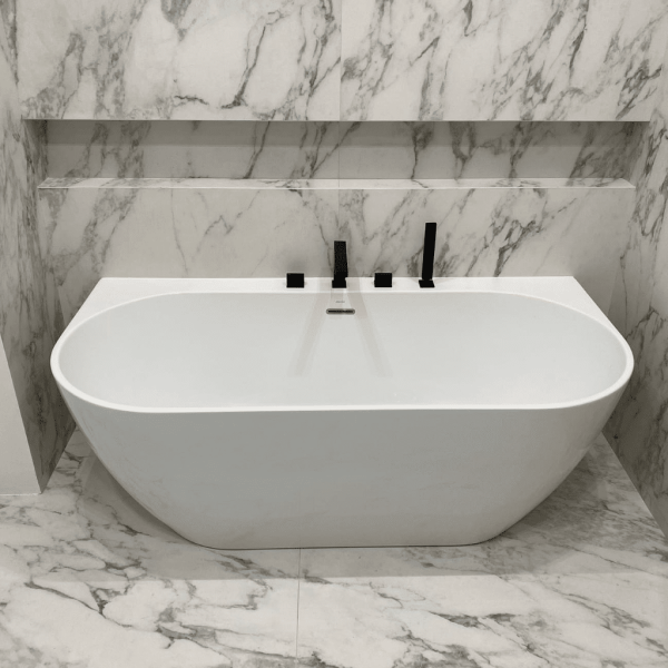 wall mount free standing bathtub with black fixtures and marble tiles
