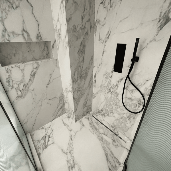 stand up shower with black shower fixtures and marble tiles